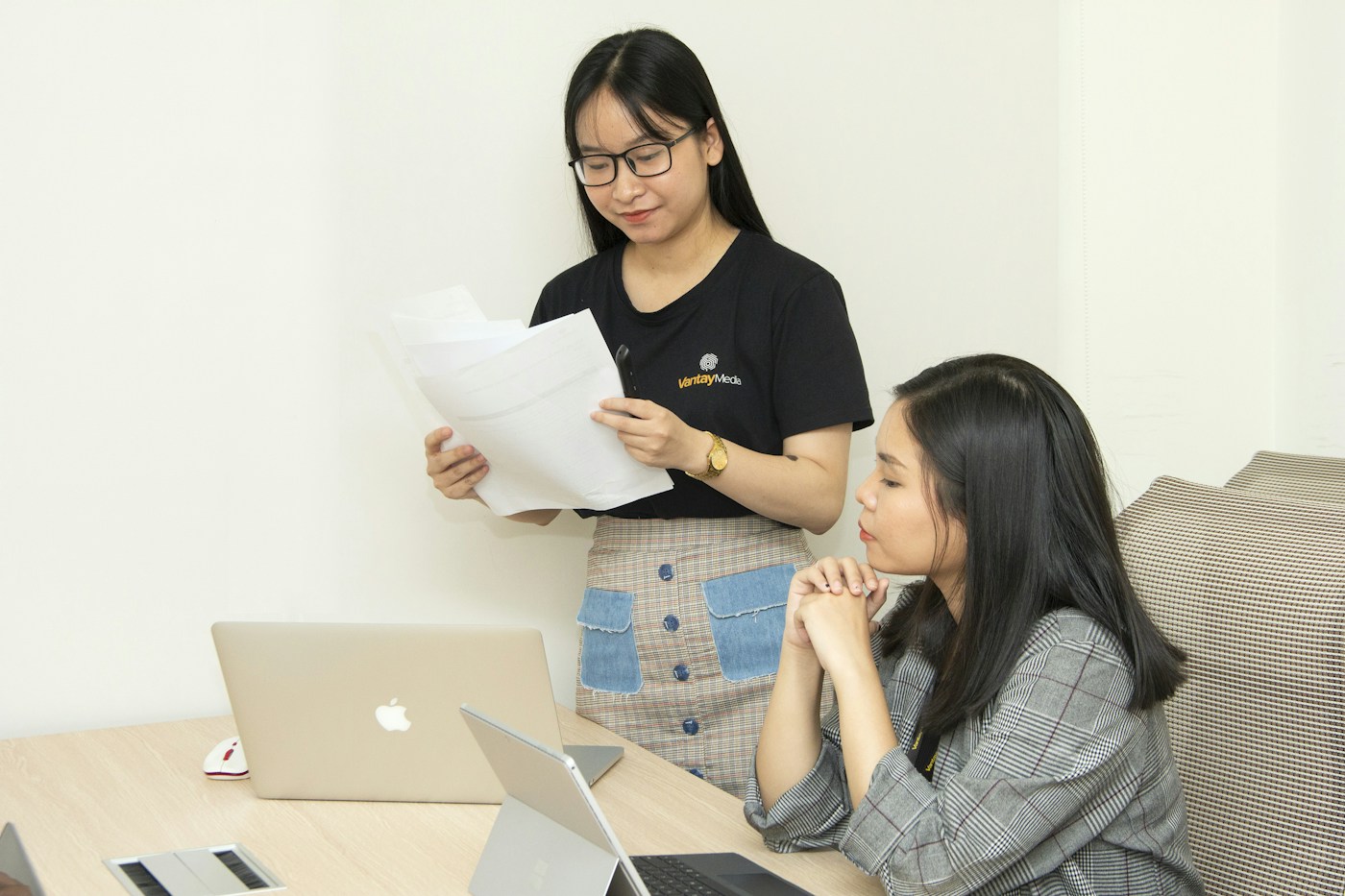 Ảnh minh họa hai đồng nghiệp tại Việt Nam trao đổi bên laptop và tài liệu